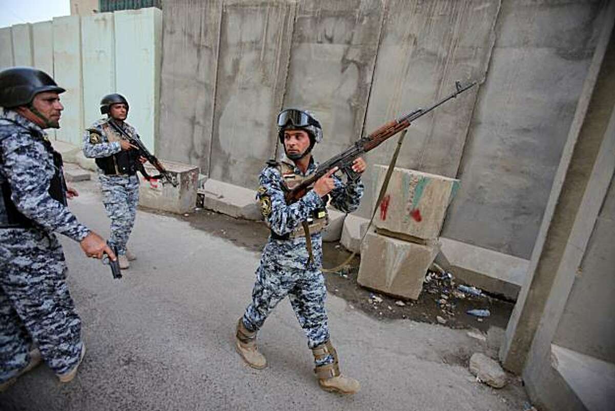 Iraqi policemen prepare to secure the scene of a string of bombings near the Central Bank of Iraq in central Baghdad, Sunday, June 13, 2010. Explosives-packed cars and roadside bombs killed a dozen people Sunday in a central Baghdad marketplace in an attack officials said appeared to target the Iraqi government's central bank.