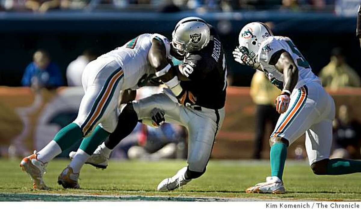 Raiders quarterback JaMarcus Russell is sacked by Dolphins Vonnie Holliday,left, and Joey Porter in the first half.