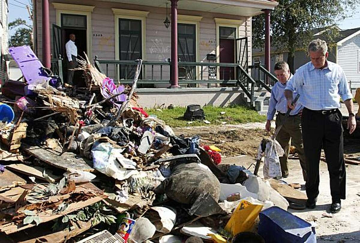 New Orleans, UNITED STATES: US President George W. Bush (R) picks up a piece of debris for a closer look as Gil Jamieson (2nd R) of Federal Emergency Management Administration (FEMA) and New Orleans mayor Ray Nagin (L) look on while touring the lower 9th Ward of New Orleans, which was heavily hit by hurricane Katrina six months ago, 08 March 2006. Bush is touring the hurricane-affected states of Louisiana and Mississippi to survey recovery efforts. AFP PHOTO/Mandel NGAN (Photo credit should read MANDEL NGAN/AFP/Getty Images)