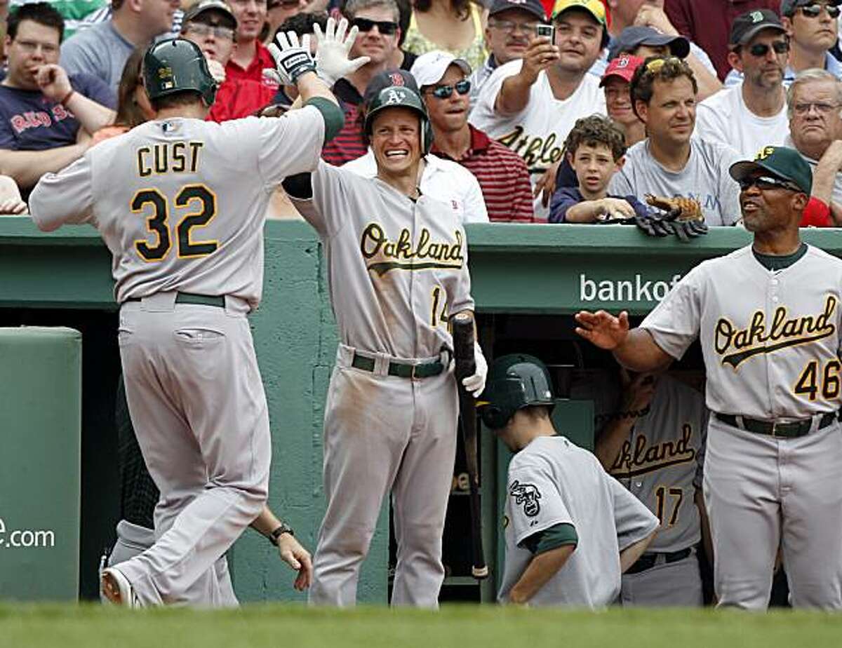 Oakland Athletics' Jack Cust, left, is welcomed into the dugout by teammate Mark Ellis, center, and Athletics bench coach Tye Waller, right, after hitting a home run off a pitch by Boston Red Sox's Manny Delcarmen in the eighth inning of a baseball game at Boston's Fenway Park, Thursday, June 3, 2010. The Athletics defeated the Red Sox 9-8.