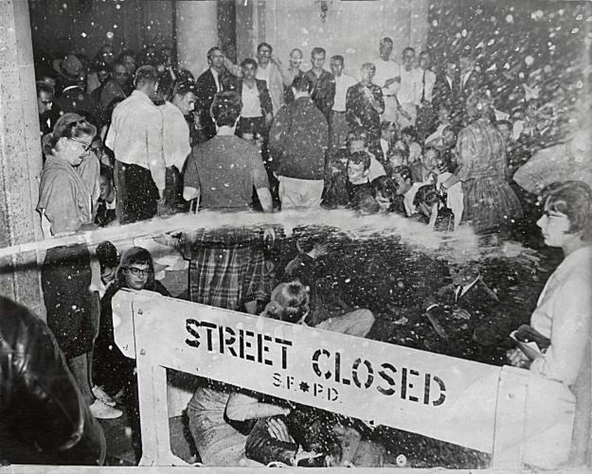 Water from a fire hose poured over a barricade onto demonstrators. Photo taken May 14, 1960.