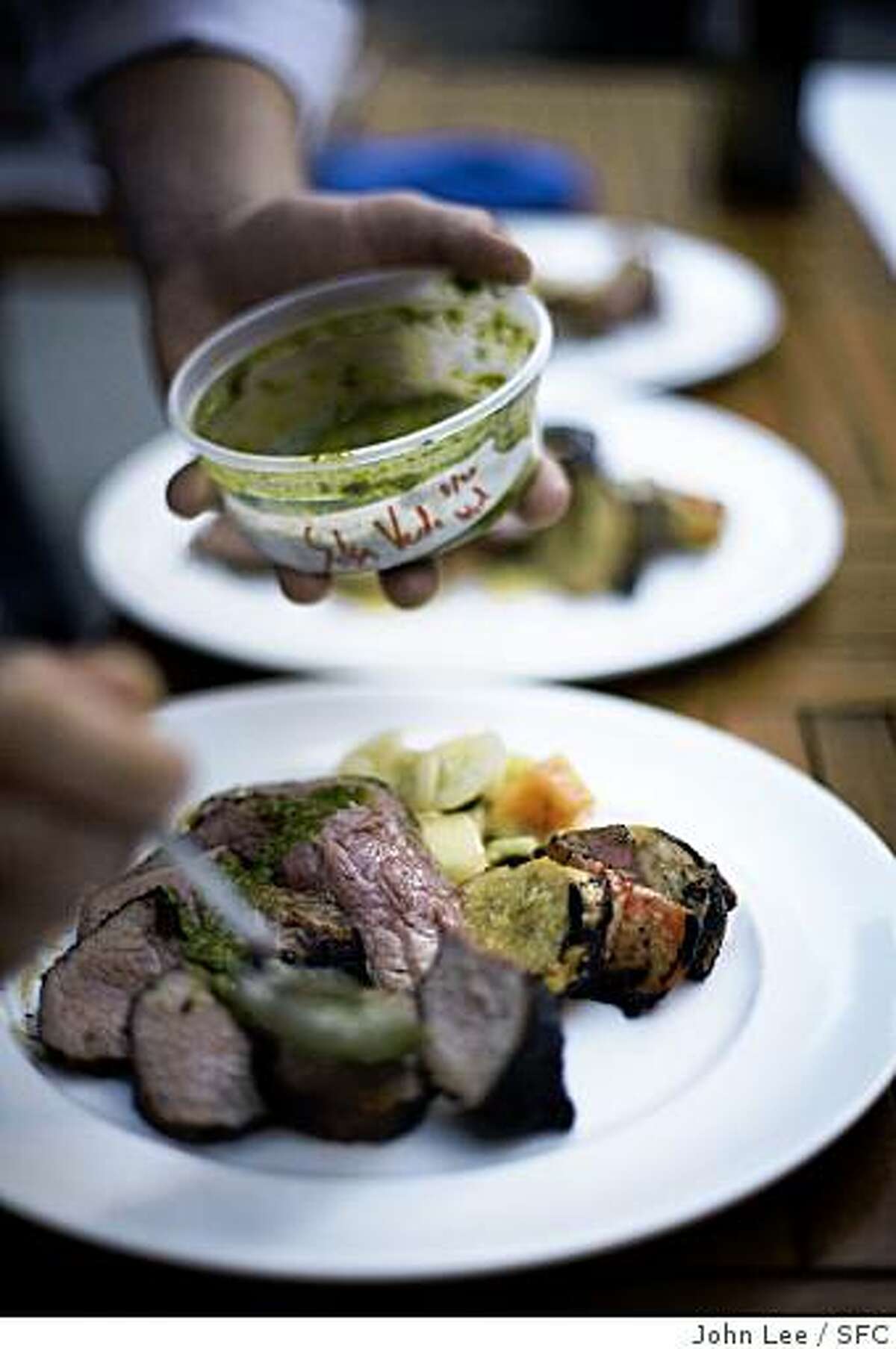 DUCCA_11_JOHNLEEPICTURES.JPG SAN FRANCISCO, CALIF - AUG 20: A cook spreads salsa verde onto some meat during Ducca's regular Wednesday evening barbecue in the restaurant's patio. BY JOHN LEE / SPECIAL TO THE CHRONICLE