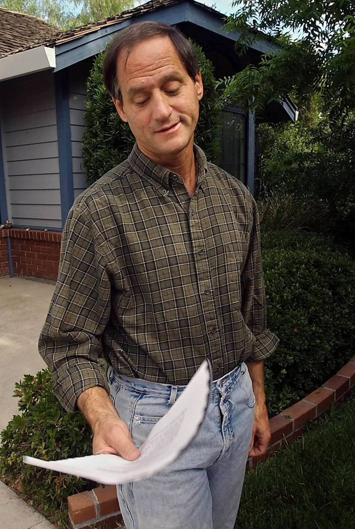 File - In this June 14, 2004 file photo, Michael Newdow looks down at the fax copy of the Supreme Court's ruling preserving the phrase "one nation under God" in the Pledge of Allegiance outside his Sacramento, Calif., home. A federal appeals court in SanFrancisco has ruled that the phrase "under God" in the Pledge of Allegiance is constitutional. In a 2-1 ruling, the 9th U.S. Circuit Court of Appeals panel rejected arguments by Newdow that the phrase violates the separation between church and state.