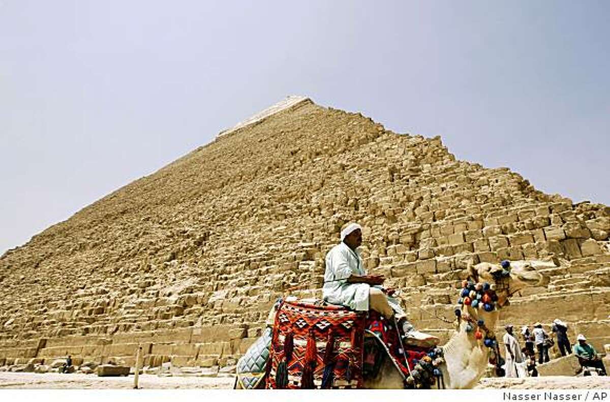 An Egyptian camel rider waits for customers at the site of the ancient Giza Pyramids in Cairo, Egypt Monday, Aug. 11, 2008. The monuments may be glorious, but visiting Egypt's famed Giza Pyramids has long been a nightmare, with hawkers peddling camel rides and pharaonic trinkets, hustling tourists relentlessly at every turn. (AP Photo/Nasser Nasser)
