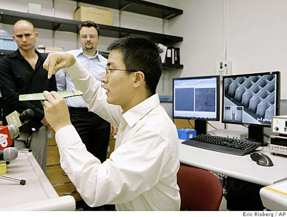 Jie Yao, right, co-author of a science paper about new materials that can bend light backwards, gives a brief demonstration as co-authors Guy Bartal, left, Jason Valentine, center, look on during a news conference in a laboratory at the University of California at Berkeley in Berkeley, Calif., Monday, Aug. 11, 2008. Scientists say they are a step closer to developing materials that could render people and objects invisible. Researchers have demonstrated for the first time they were able to cloak three-dimensional objects using artificially engineered materials that redirect light around the objects. The new work moves scientists a step closer to hiding people and objects from visible light, which could have broad applications, including military ones. (AP Photo/Eric Risberg)