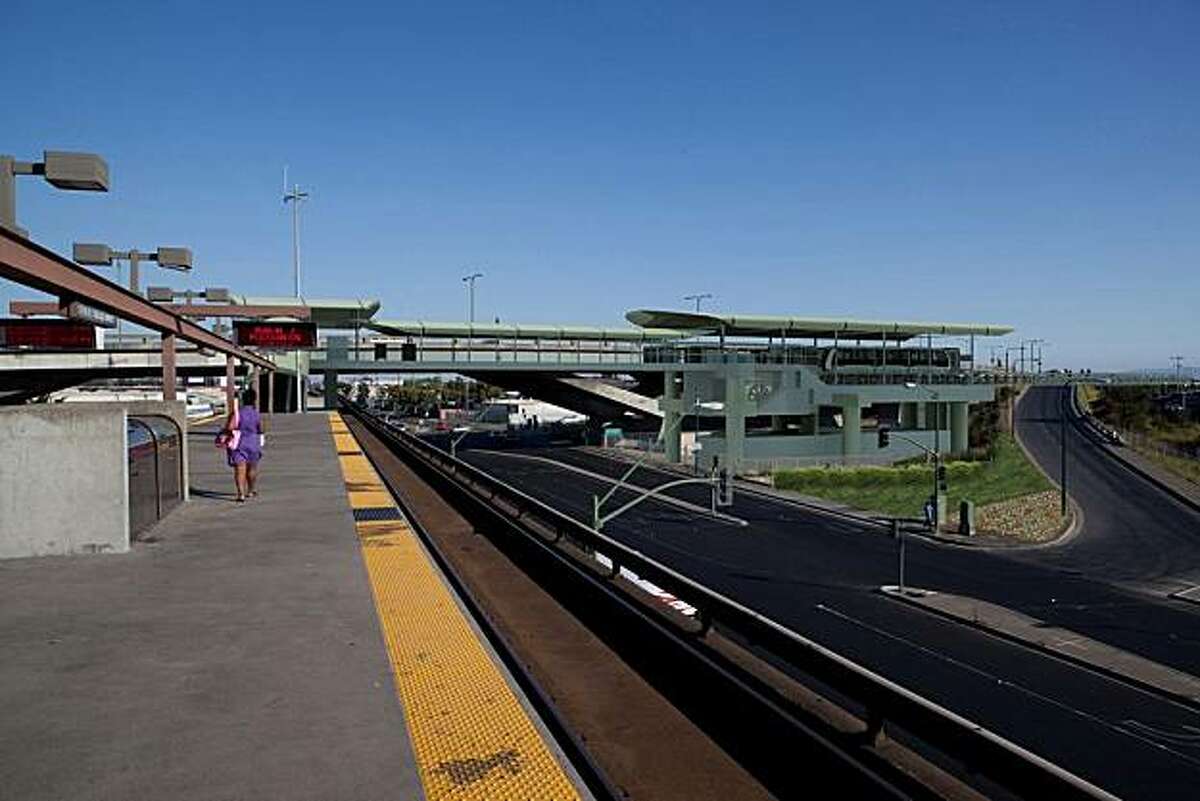 An artist's rendering shows the Oakland Airport Connector - Coliseum Station shown connecting to the southern end of the existing BART Platform via a short escalator ride up to a pedestrian overcrossing of San Leandro Blvd. The view is from the BART platform looking south towards the new OAC station.
