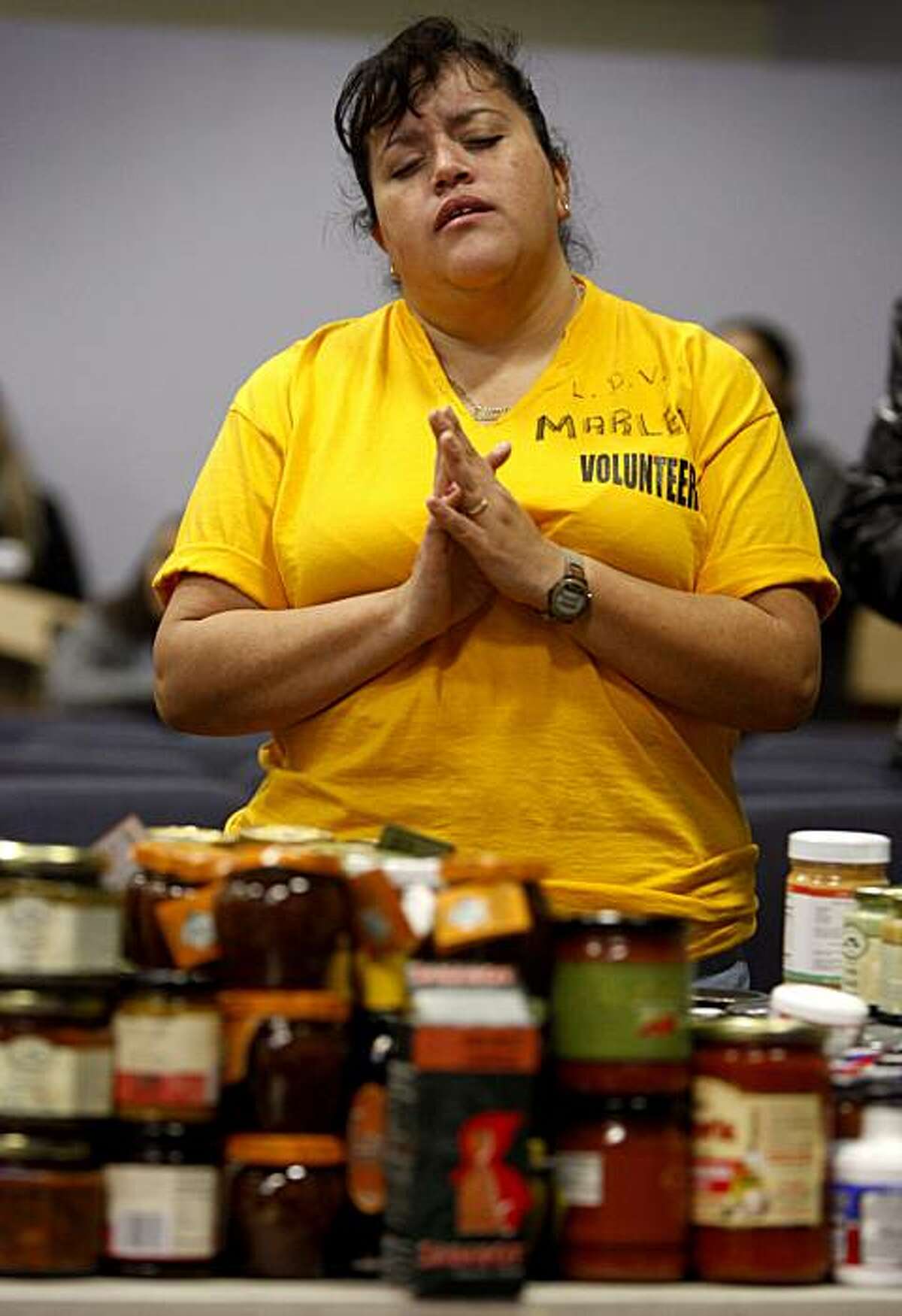 Volunteer Marlene Rojas prays before helping distribute free food to parishioners in Hayward, Calif., on Saturday, Jan. 23, 2010. The Bay Area Dream Center distributed as many as 5,000 bags of free groceries, donated by vendors from a fancy food trade show, to those who attended a 20-minute religious service.