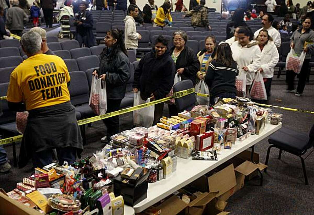 People wait in line to collect free food in Hayward, Calif., on Saturday, Jan. 23, 2010. The Bay Area Dream Center distributed as many as 5,000 bags of free groceries, donated by vendors from a fancy food trade show, to those who attended a 20-minute religious service.