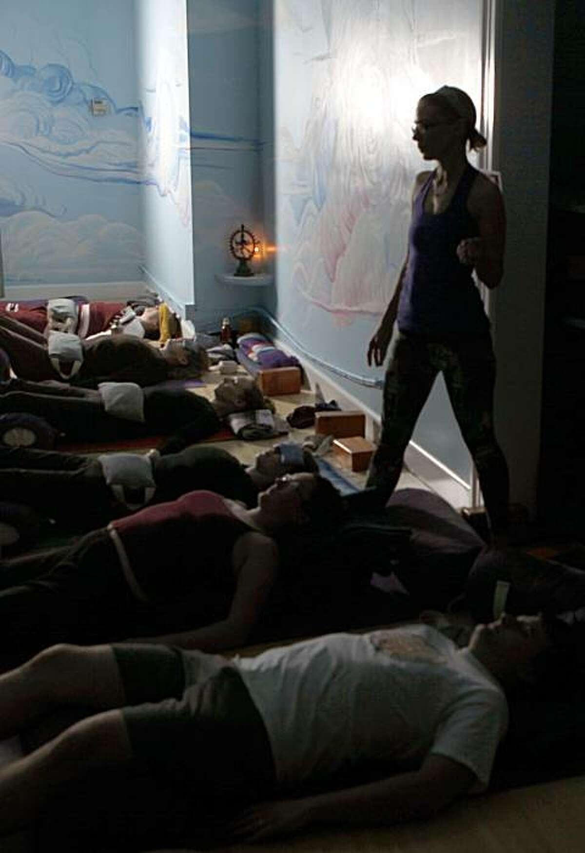 Elise Collins standing, teaches a new form of Yoga called Restorative Yoga - which is basically napping for grownups. People get in various positions of repose - on pillows, blankets and some wearing eye pillows, and chill out at Stanyan Yoga Tree in San Francisco Saturday Jan. 9, 2010