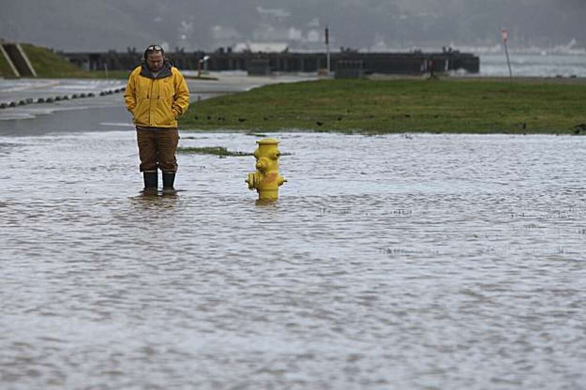 During a calm in the first of several storms expected to hit the Bay Area, Andrew Baird of the Presidio Trust checks on a drainage problem on Mason Street near Crissy Field on Monday.