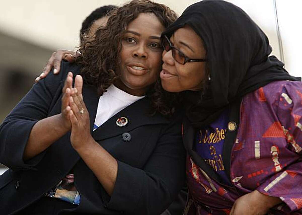 The mother of Oscar Grant, Wanda Johnson, (left) gets a hug from Lorrain Taylor as they join a crowd of family, friends and supporters for a vigil to remember her son, at the Fruitvale BART station on Friday January 1, 2010, in Oakland, Ca., a year after Grant was shot and killed early New years Day 2009.