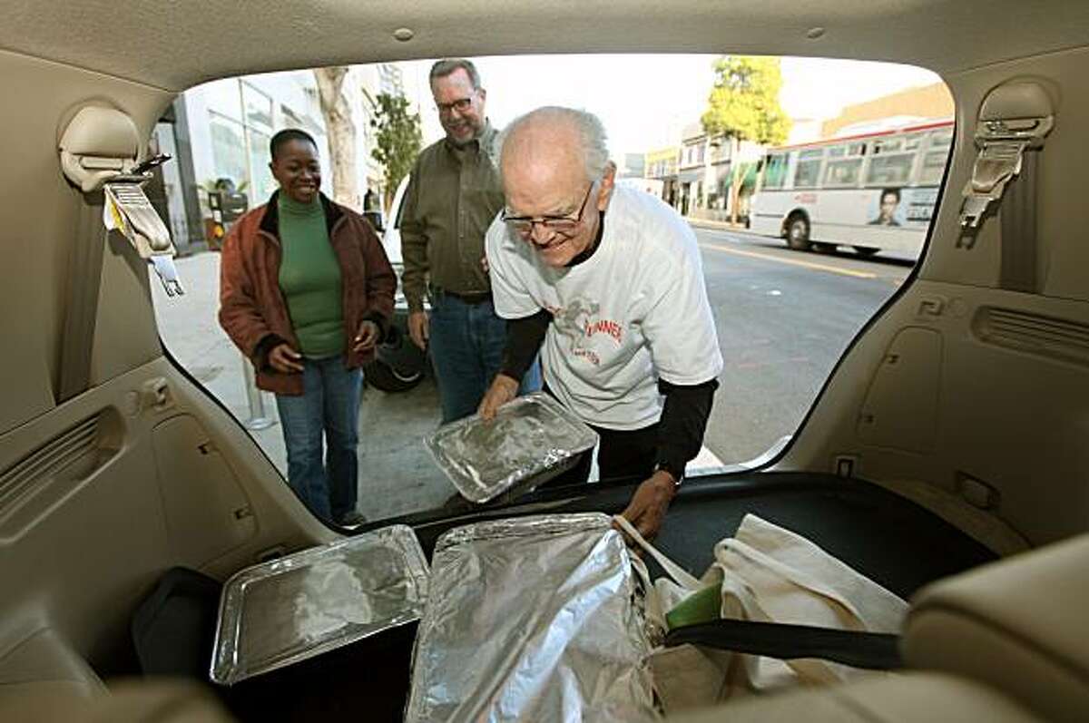 Sam Haskins, a volunteer food runner gets help from Patricia Nevtall a nurse and Charles Clongier the Clinical Director of St. James Infirmary as they unload hot dishes from Kokkari Restaurant on Jackson Street Dec 17, 2009