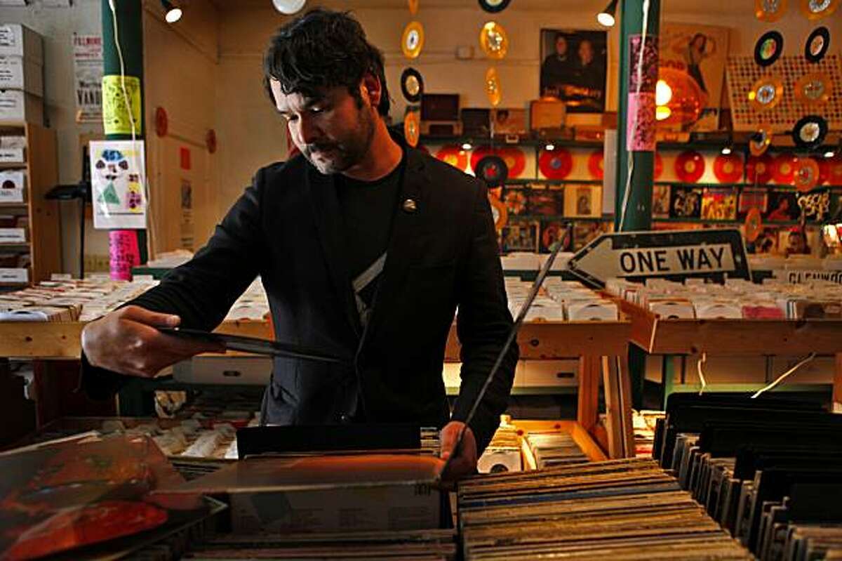 Julio Cesar Morales, arts curator at Yerba Buena Center for the Arts, listens to albums at one of his favorite places, Rooky Ricardo's Records, Thursday Nov. 12, 2009, in San Francisco, Calif.
