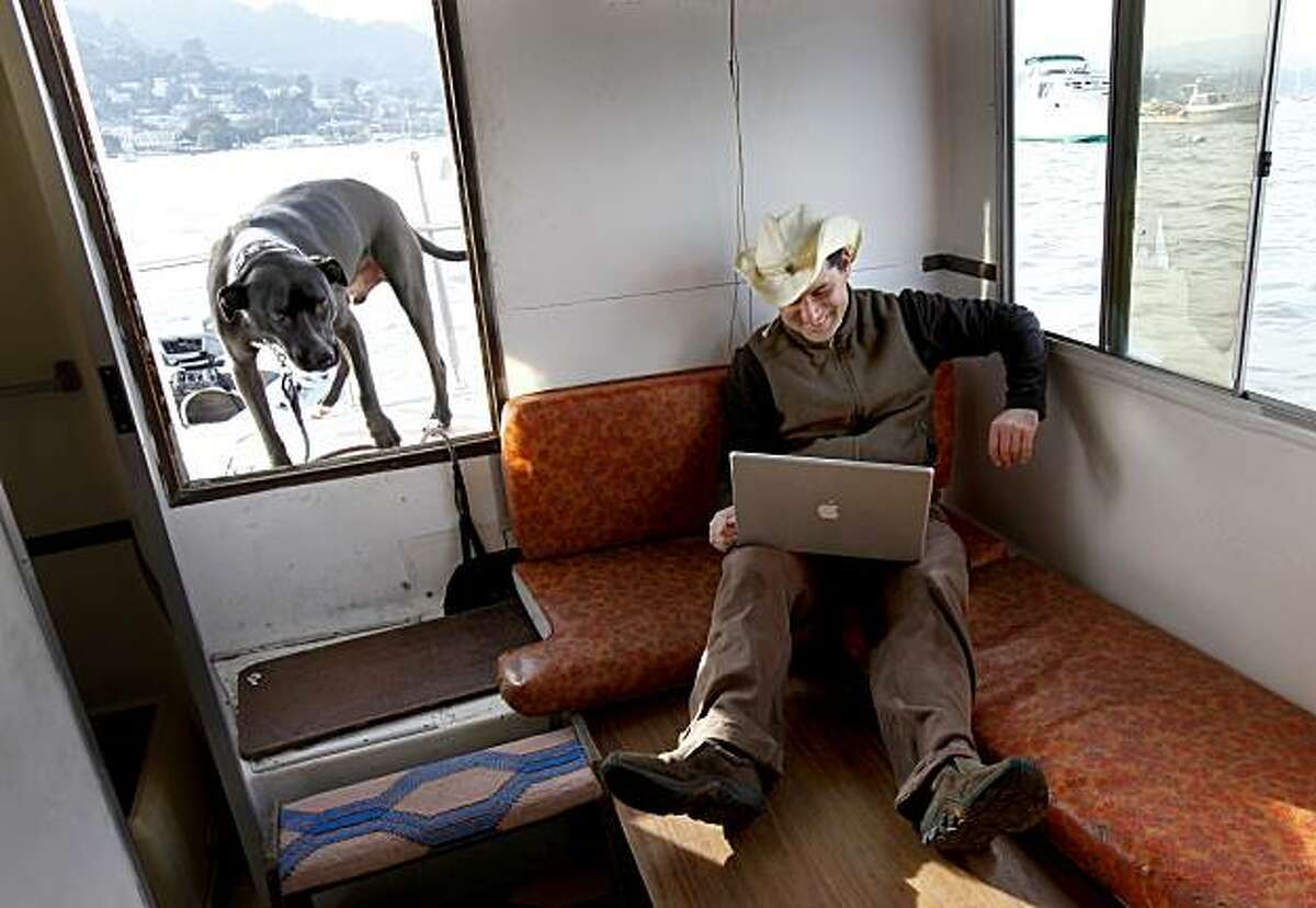 Weissleder works on his Apple computer using a wireless card. Myles Weissleder uses a floating office, a houseboat anchored off Sausalito, for his technology business. He regularly commutes to the houseboat from a tender with his trusty dog Pico.