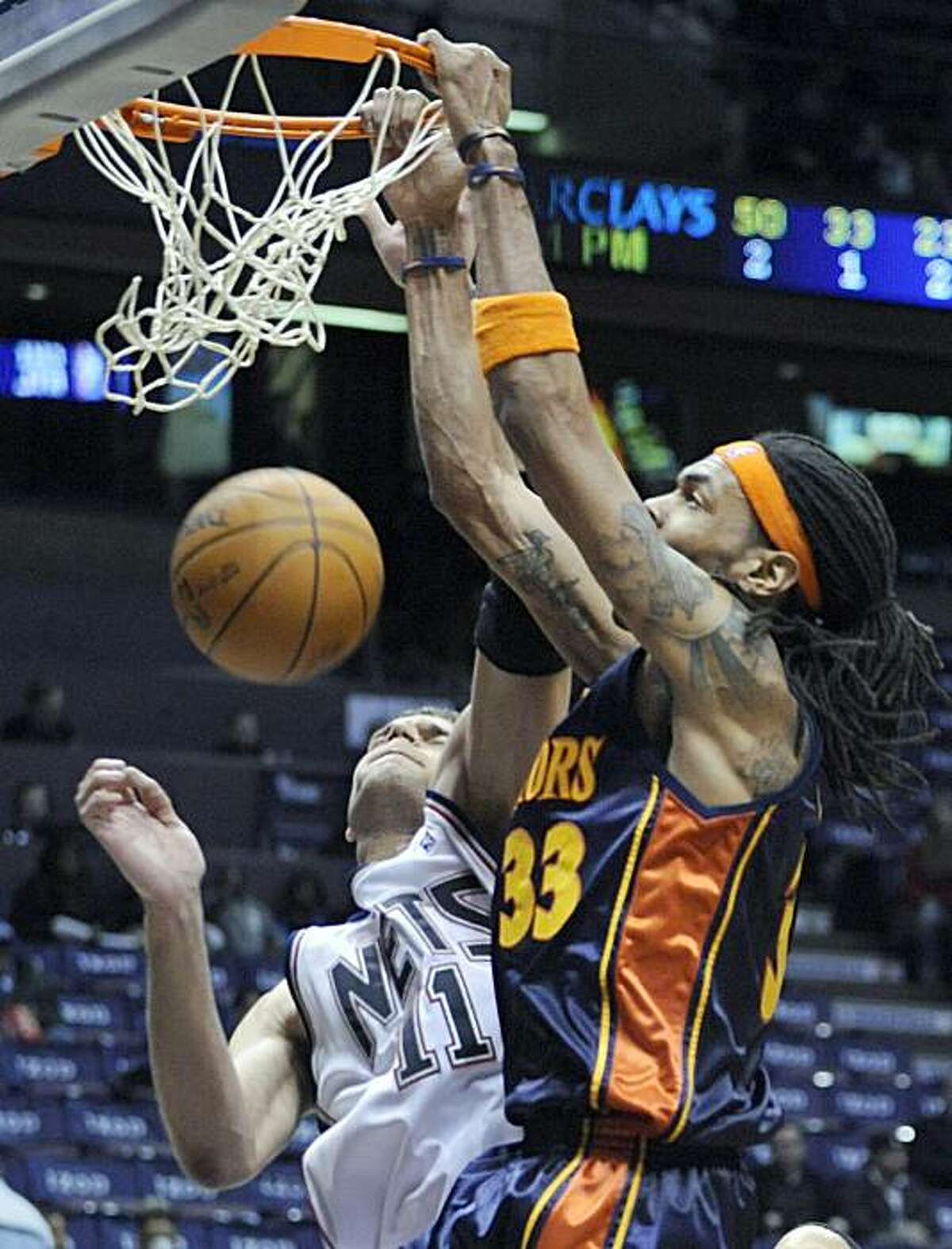 Golden State Warriors' Mikki Moore, right, dunks the ball over New Jersey Nets' Brook Lopez during the fourth quarter of an NBA basketball game Wednesday, Dec. 9, 2009 in East Rutherford, N.J. The Warriors beat the Nets 105-89. (AP Photo/Bill Kostroun)