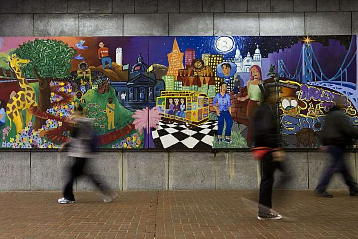 Pedestrians stroll past a mural in Hallidie Plaza, the sunken plaza leading into the Powell BART/Muni Station, on Monday, Nov. 30, 2009. The plaza is slated for a revamp starting with the little-used western portion close to Cyril Magnin Street. Mayor Gavin Newsom and other city officials want to remake the plaza starting with the decking area so it will be level with the street.