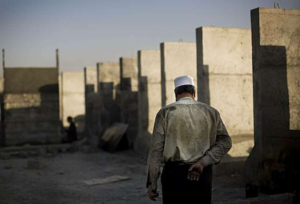 An Afghan worker passes by concrete blast walls in the outskirts of Kabul, Afghanistan, Tuesday, Nov. 17, 2009. With security worsening and thousands of international troops being additionally expected by next year, business is going up for concrete blast walls. (AP Photo/Anja Niedringhaus)