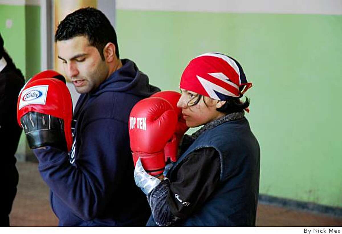 Concord native Tareq Shawl Azim teaches 15-year-old Shabnam Rahimi how to box at the National Stadium in Kabul.