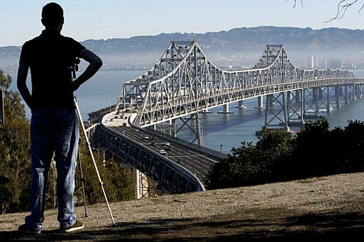 San Francisco State student Derek Highsmith watch with his video camera as commuter driver over the Bay Bridge since it reopened from emergency repairs on Monday, Nov. 2, 2009 in San Francisco, Calif.