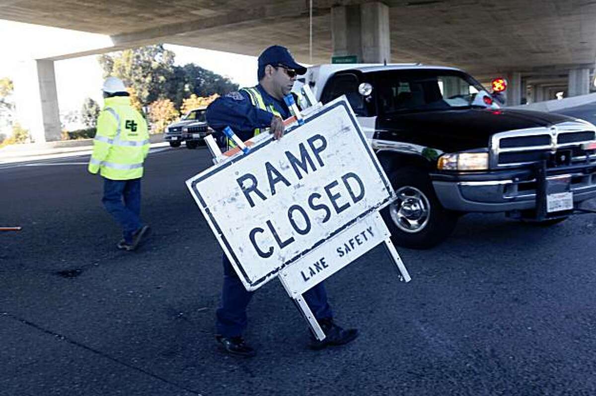 As drivers lineup in anticipation of the official reopening of the Bay Bridge, California Highway Patrol officer, Rod Rodriguez moves the final road block to the West Oakland entrance of the bridge on Monday, Nov. 2, 2009 in Oakland, Calif.