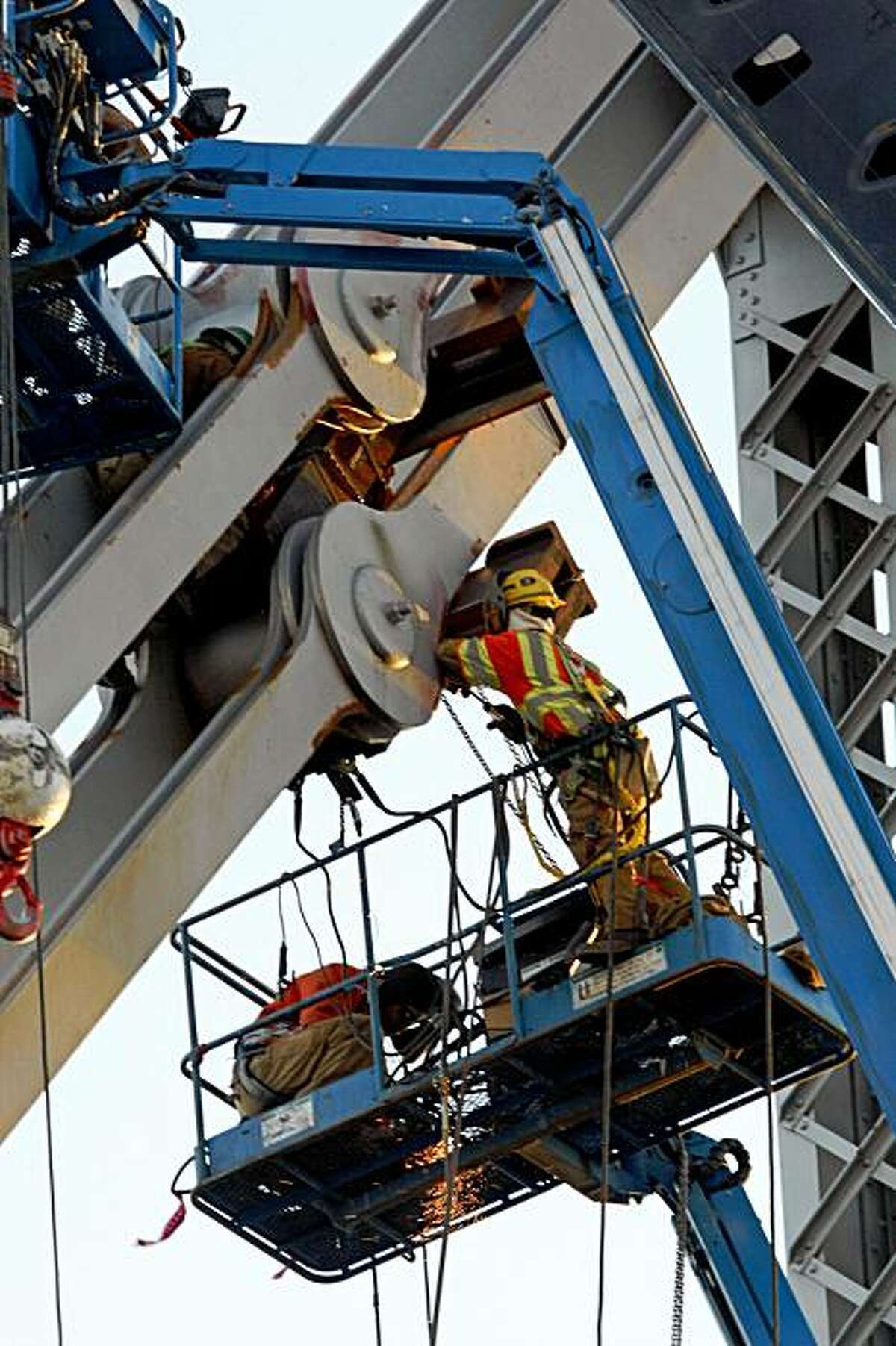 Ironworkers work on the saddle and tie-rods that failed on the Bay Bridge.