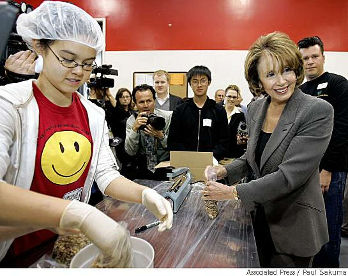 House Speaker Nancy Pelosi of Calif., right, helps volunteer Emma Levine, 13, of the Chinese American International School, pack pinto beans at the San Francisco Food Bank in San Francisco, Friday, May 30, 2008. After Pelosi's tour, she spoke at a news conference about delegates. (AP Photo/Paul Sakuma)