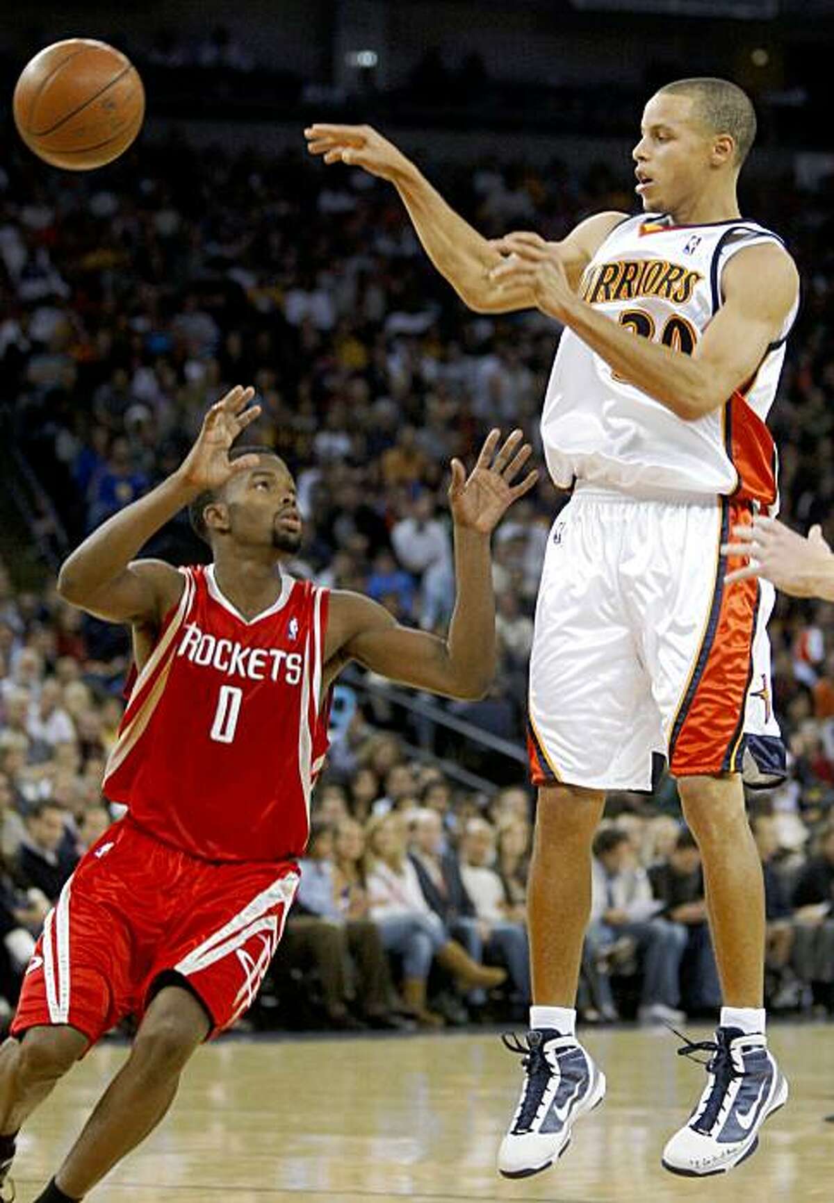 Golden State Warriors' Stephen Curry, right, passes away from Houston Rockets' Aaron Brooks during the second half of an NBA basketball game Wednesday, Oct. 28, 2009, in Oakland, Calif. (AP Photo/Ben Margot)