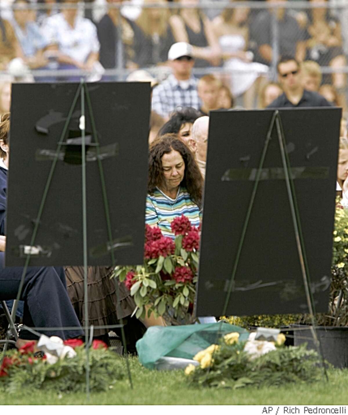Jodie Carrigan is seen between a pair of photographs of her deceased children during a memorial service at football field at Chester Junior-Senior High School in Chester, Calif., Tuesday, May 20, 2008. On Mother's day Jodie Carrigan found the bodies of her daughter Jenny, 18, and a friend, Steven Furtado,18, at the Carrigan home in Chester. Later the same day Jodie's son, Billy, 20, was fatally injured in a car accident while returning home from Berkeley. Reyes Carrillo, 18, a classmate and former boyfriend of Jenny Carrigan, has been charged in the murders.(AP Photo/Rich Pedroncelli)