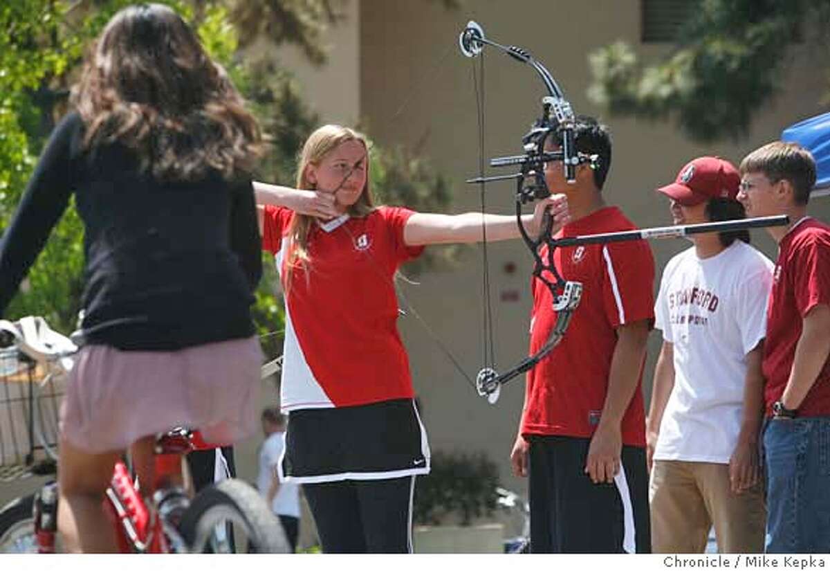 In an effort to recruit new students touring Stanford's campus, Katherine Boren, with the Stanford Archery Club, joins hundreds of other members of various student groups at White Plaza on Thursday April, 24, 2008 in Stanford, Calif. The number of student groups at Stanford and Cal have more than doubled in the last 10 years. will be out in force on White Plaza. Photo by Mike Kepka / San Francisco Chronicle Ran on: 05-19-2008 Katherine Boren of Stanford Archery demonstrates the sport to incoming students at a recruitment event on campus.