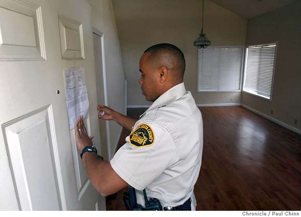 Contra Costa County Sheriff's deputy Doug Odom posts an eviction notice on a home in Antioch, Calif., on Tuesday, Feb. 26, 2008. The tenants had already moved out when the deputies arrived. Photo by Paul Chinn / San Francisco Chronicle Ran on: 03-09-2008 Ellen Anderson takes one last look around before being evicted, above. Deputies Doug Odom (left) and Alex Custodio enter a home to evict people in Antioch, below left. An eviction noticed is left behind in Brentwood, below right. Ran on: 03-08-2008