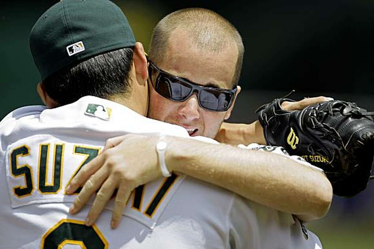 Jon Wilhite, right, former Cal State Fullerton baseball star, embraces his former teammate, Oakland Athletics catcher Kurt Suzuki, after throwing out the ceremonial first pitch before a baseball game between the A's and the Los Angeles Angels, Saturday, July 18, 2009, in Oakland, Calif. Wilhite is the sole survivor of the April 9 car crash that killed Angels pitcher Nick Adenhart, Henry Pearson and Courtney Stewart. (AP Photo/Ben Margot)