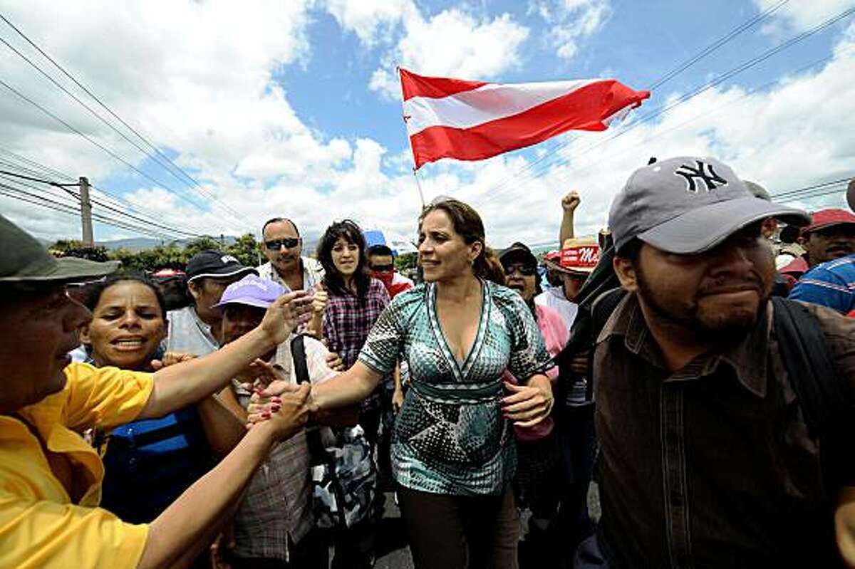 The wife of Honduran ousted President Manuel Zelaya, Xiomara Castro de Zelaya (C), joins supporters of her husband protesting in Tegucigalpa on July 18, 2009. Honduras's military was on alert Saturday for a possible return attempt by Zelaya, as talks between his aides and the country's de facto government were held in Costa Rica. Tensions were ratcheted up after days of protests by thousands of Zelaya supporters who blocked roads around the capital. AFP PHOTO/Orlando SIERRA (Photo credit should read ORLANDO SIERRA/AFP/Getty Images)