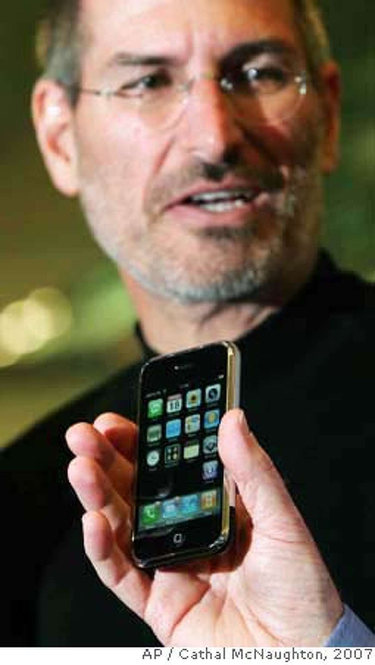 ###Live Caption:Apple CEO Steve Jobs is seen at the Apple store on Regent Street for the announcement of its long-awaited iPhone, as an unidentified person holds up the device in the foreground, London, Sept. 18, 2007. Apple Inc.'s iPhone will go on sale in Britain on Nov. 9 and have the O2 network as its exclusive carrier, Apple CEO Steve Jobs said Tuesday. The 8-gigabyte model will sell for 269 pounds (US$536, euro 386). (AP Photo/PA, Cathal McNaughton) ** UNITED KINGDOM OUT NO SALES NO ARCHIVE ** Ran on: 09-19-2007 Apple CEO Steve Jobs appears at an Apple store in London to announce plans to sell the iPhone in Britain through carrier O2, without the discounts typical of even high-end phones in Europe.###Caption History:Apple CEO Steve Jobs is seen at the Apple store on Regent Street for the announcement of its long-awaited iPhone, as an unidentified person holds up the device in the foreground, London, Sept. 18, 2007. Apple Inc.'s iPhone will go on sale in Britain on Nov. 9 and have the O2 network as its exclusive carrier, Apple CEO Steve Jobs said Tuesday. The 8-gigabyte model will sell for 269 pounds (US$536, euro 386). (AP Photo/PA, Cathal McNaughton) ** UNITED KINGDOM OUT NO SALES NO ARCHIVE ** Ran on: 09-19-2007 Apple CEO Steve Jobs appears at an Apple store in London to announce plans to sell the iPhone in Britain through carrier O2, without the discounts typical of even high-end phones in Europe.###Notes:###Special Instructions:UNITED KINGDOM OUT NO SALES NO ARCHIVE - PHOTOGRAPH CAN NOT BE STORED OR USED FOR MORE THAN 14 DAYS AFTER THE DAY OF TRANSMISSION