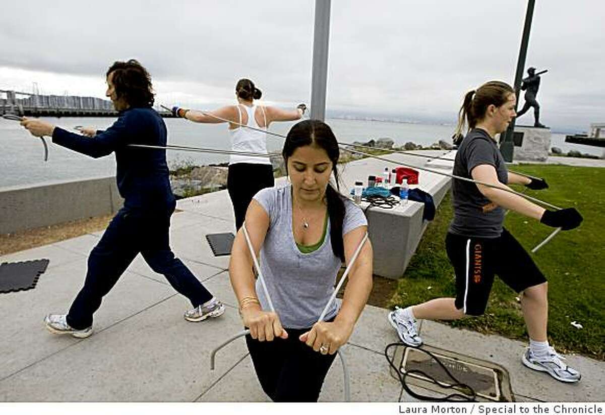 Goli Shariat (center) works on a strength exercise with others during a fitness class organized by BootCampSF outside at China Basin in San Francisco, Calif., on Friday, June 12, 2009.