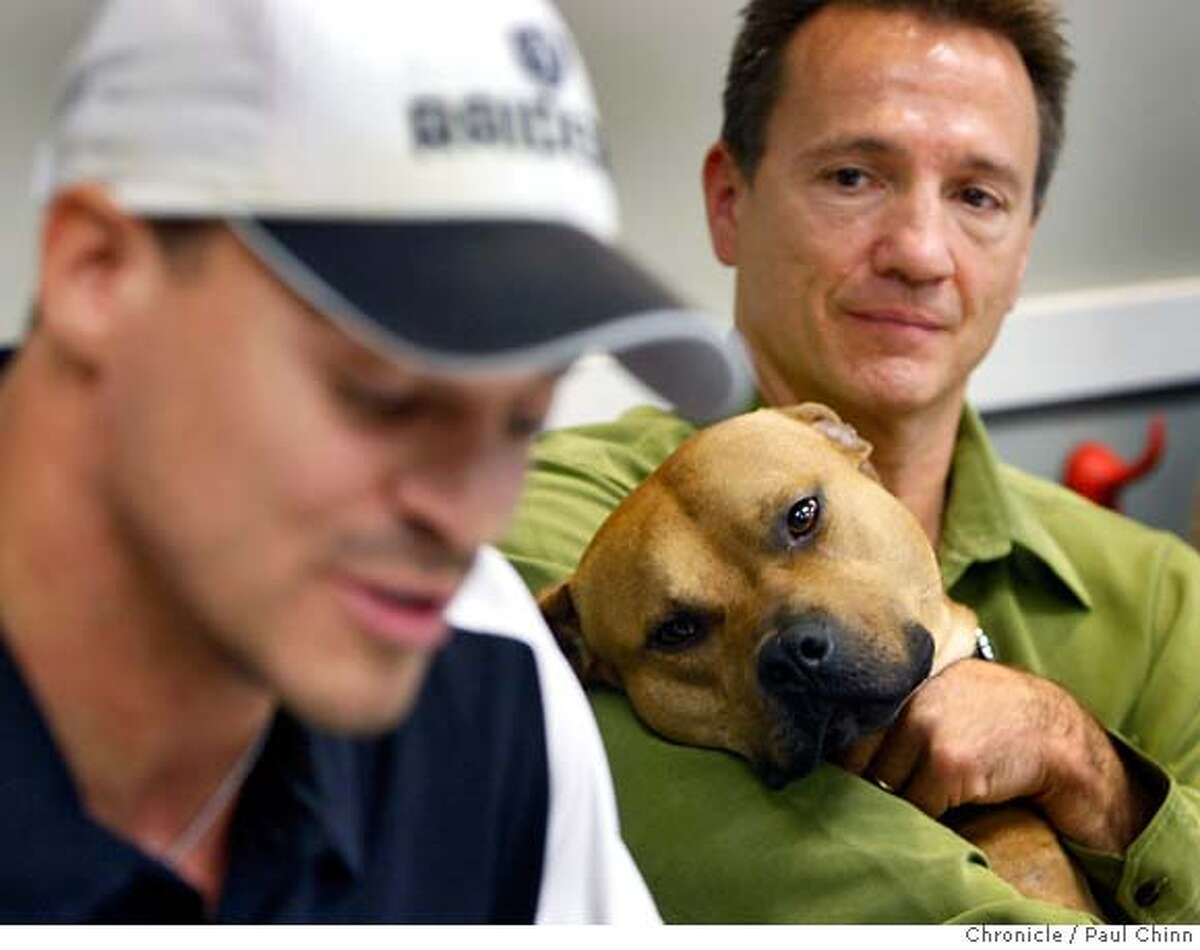 Tim Racer, co-founder of the dog rescue group BAD RAP, holds Hector while Oakland Raiders player Jarrod Cooper, left, speaks at a news conference about five pit bulls rescued from former Atlanta Falcons quarterback Michael Vick's Bad Newz Kennels in Oakland, Calif. on Friday, Jan. 25, 2008. The dogs will now be available for adoption through the BAD RAP organization.