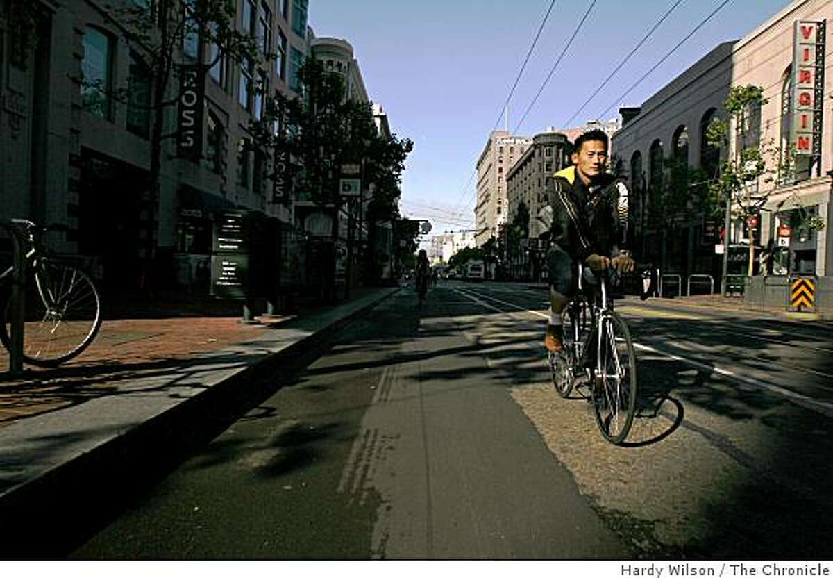 A bicyclist is illuminated by early morning light as he cycles down Market Street during Bike to Work day.