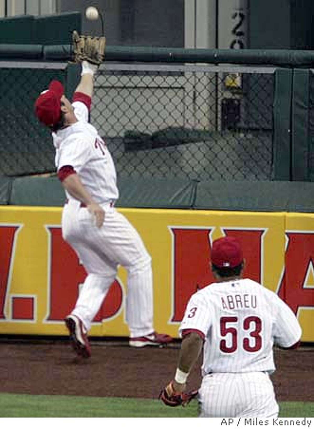 Philadlephia Phillies' Bobby Abreu, right, watches as teammate center fielder Aaron Rowand makes a catch against the wall of a drive by New York Mets' Xavier Nady in the first inning of their baseball game Thursday, May 11, 2006, in Philadelphia. Rowand was injured and left the game. (AP Photo/Miles Kennedy)