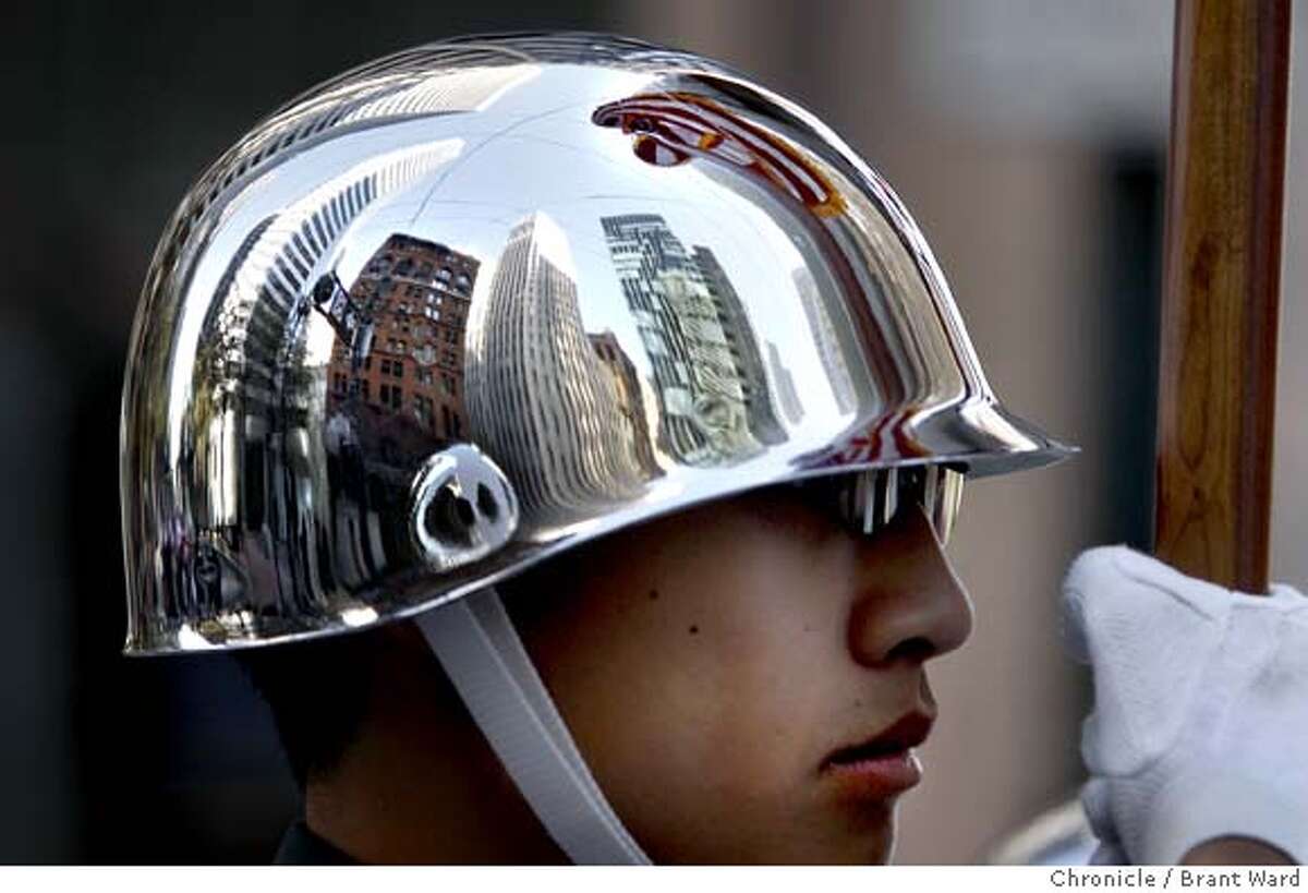 veterans_556.JPG The tall buildings of San Francisco were reflected in the helmet of Phelan Guan, who has been with the Lowell High School ROTC program for two years. He held an American flag as he marched down Market Street. 100 veterans groups and their supporters marched down Market Street Sunday in the annual Veterans Day parade. For the San Francisco high school ROTC members who marched, this may be their last parade because the programs are having funding problems. {By Brant Ward/San Francisco Chronicle}11/11/07