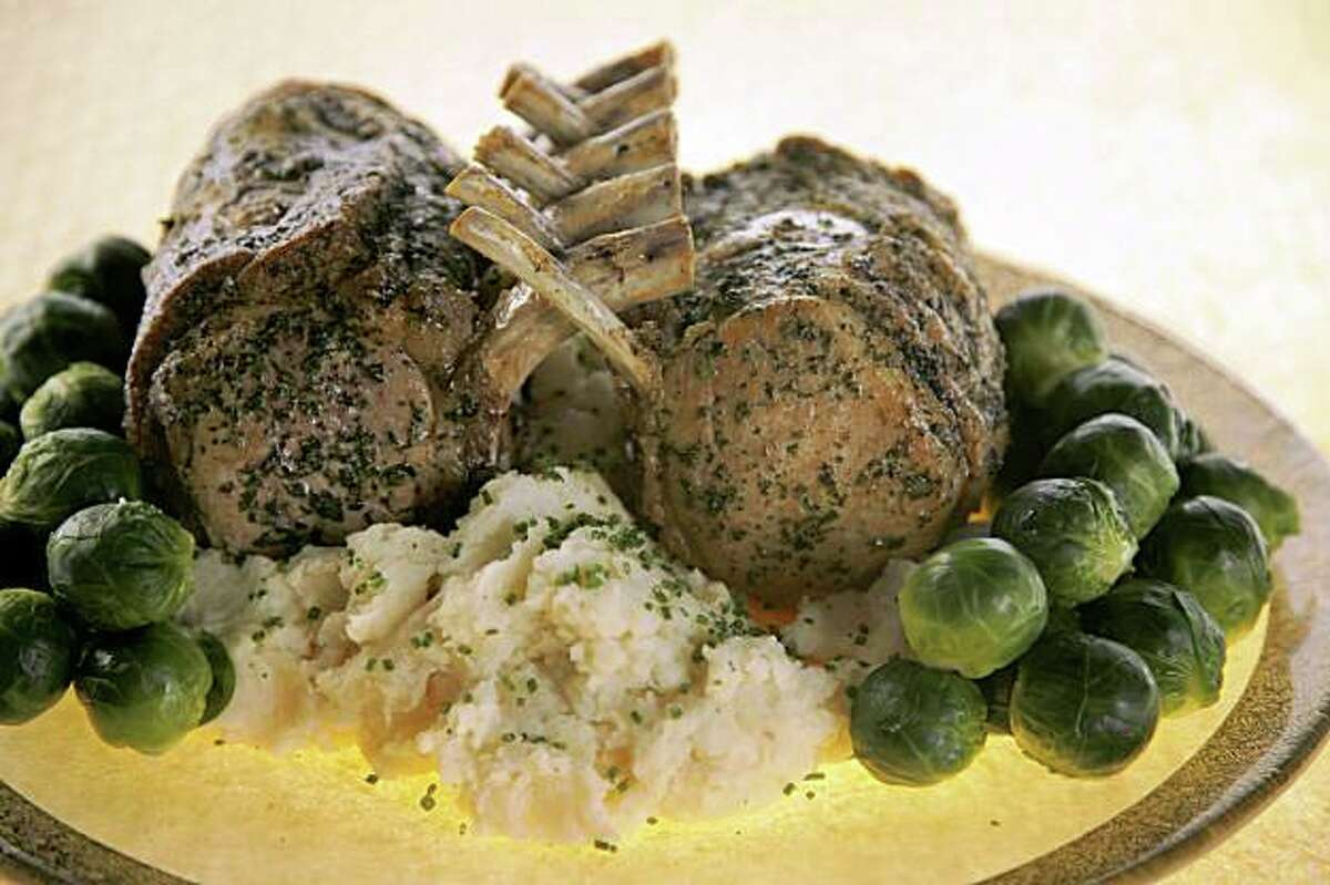 Herbed Pork "Guards in Honor" Roast on mashed potatoes with vegetables garnished around.