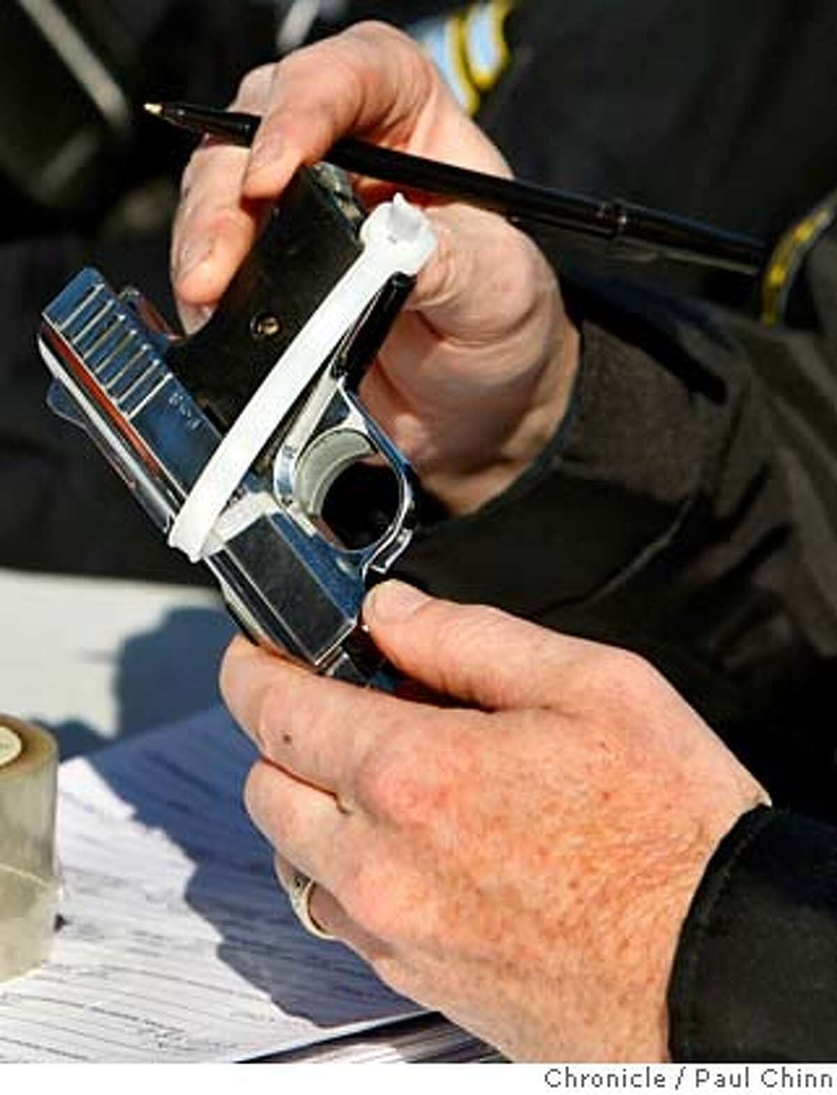A police officer checks the serial number of a handgun turned in by a resident in exchange for gift cards at the Gifts for Guns program at Civic Center Plaza in San Francisco, Calif. on Saturday, Dec. 1, 2007. It was the second exchange program sponsored by the Mayor's Office of Criminal Justice this year. PAUL CHINN/The Chronicle