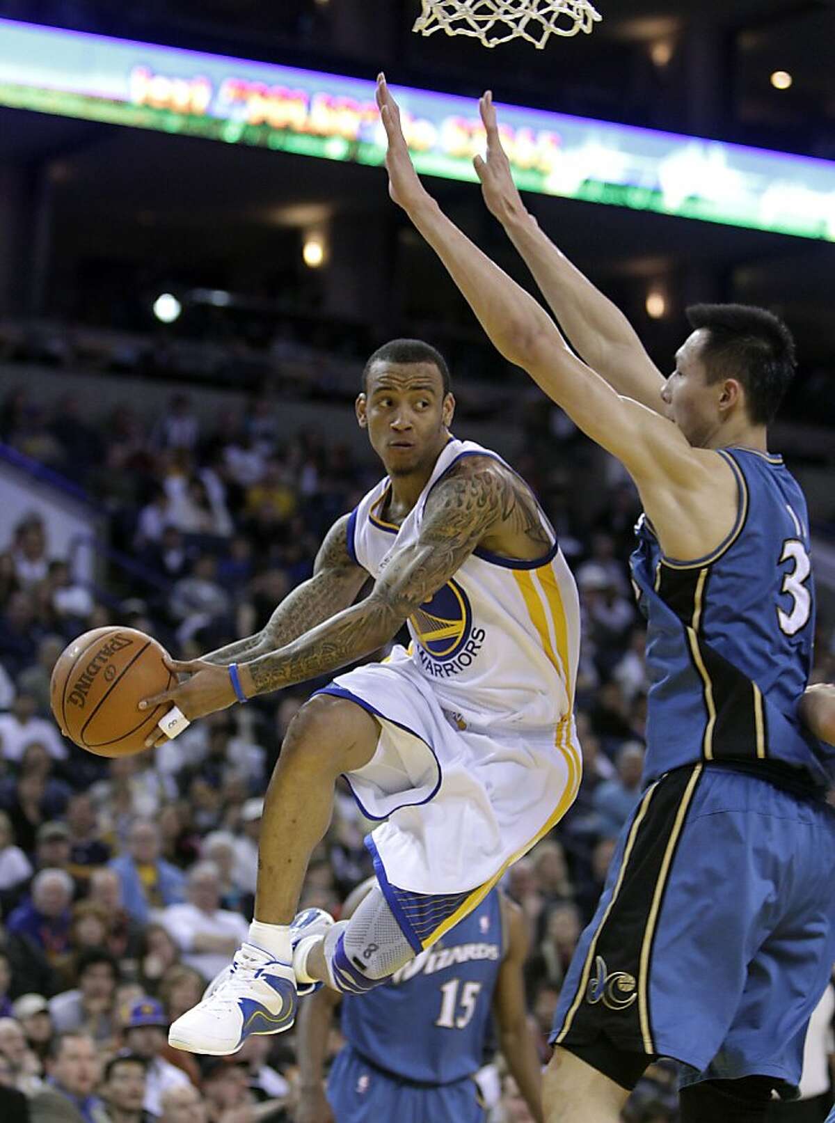 Golden State Warriors' Monta Ellis, left, looks to pass away from Washington Wizards' Yi Jianlian, of China, during the first half of an NBA basketball game, Sunday, March 27, 2011, in Oakland, Calif.