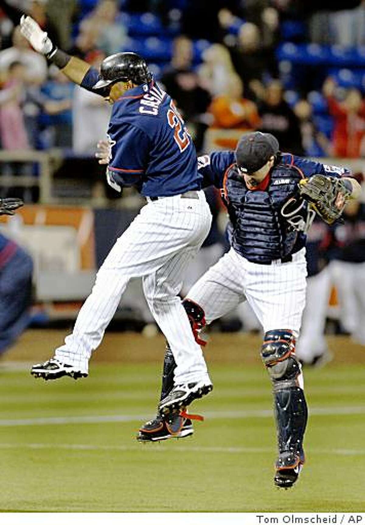 Minnesota Twins' Alexi Casilla, left, celebrates with bullpen catcher Mike Redmond after Casilla singled in two runs in the ninth inning to give the Twins a 6-5 win over the Seattle Mariners in a baseball game Tuesday, April 7, 2009, in Minneapolis. (AP Photo/Tom Olmscheid)