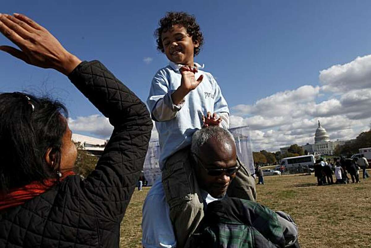 Joel Thesiger, 6, center, who has autism, gets a high-five while being carried by his father, Paul Thesiger, of Silver Spring, Md., at the end of the "Walk Now for Autism Speaks" event on the National Mall in Washington, on Saturday, Nov. 6, 2010. The three-mile walk funds research and raises awareness of autism.
