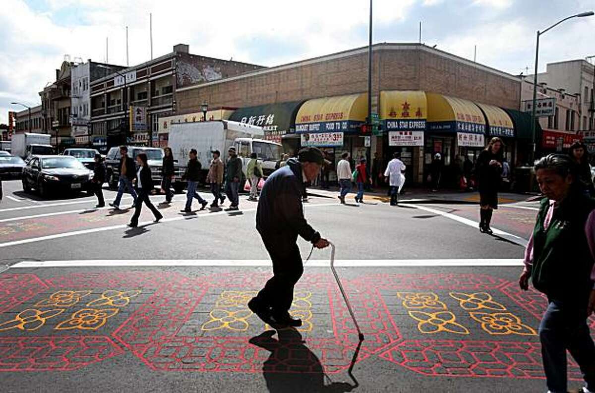 A man crosses the street in the Chinatown district in Oakland, Calif. on Tuesday, March 17, 2009