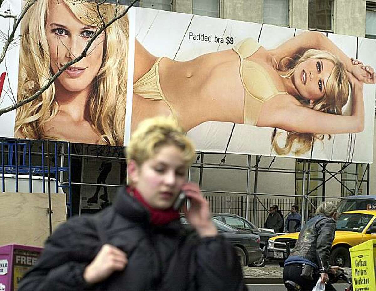 383191 02: A woman speaks on her cell phone in front of a billboard featuring model Claudia Schiffer advertising the winter underware collection of clothing retailer H&M December 12, 2000 in New York City. (Photo by Chris Hondros/Newsmakers)
