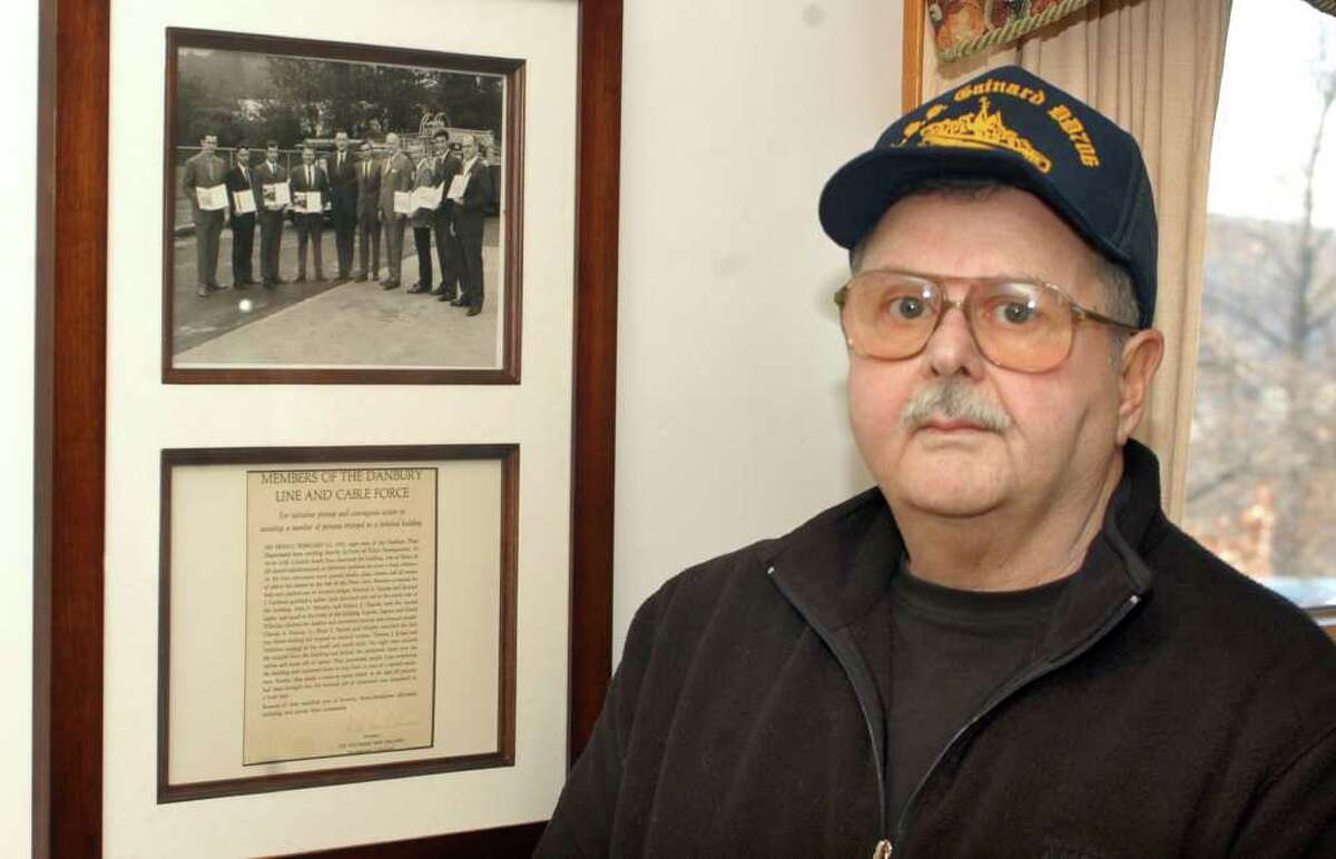 Retired telephone company lineman Robert Ingram with a framed photograph of the members of his SNET crew that rushed into the bomb-shattered Danbury police station on Feb. 13, 1970 to help victims of the explosion set off by brothers James and John Pardue to cover a robbery at the Union Savings Bank.