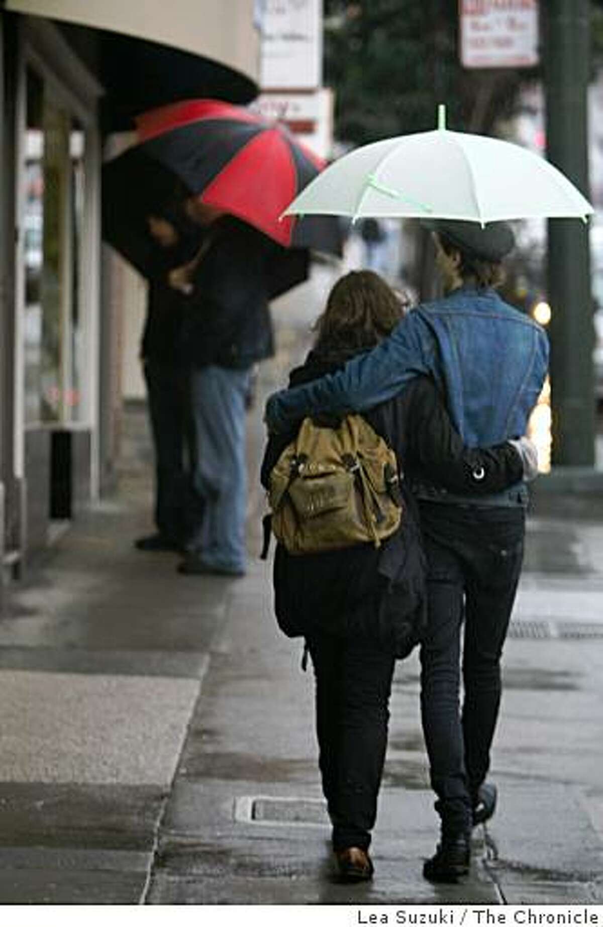 Victoria Sim ( to r) and Lynn Tolliver of Montreal, Canada share an umbrella as they walk in the rain on Castro Street in San Francisco, Calif. on Sunday, February 22, 2009.