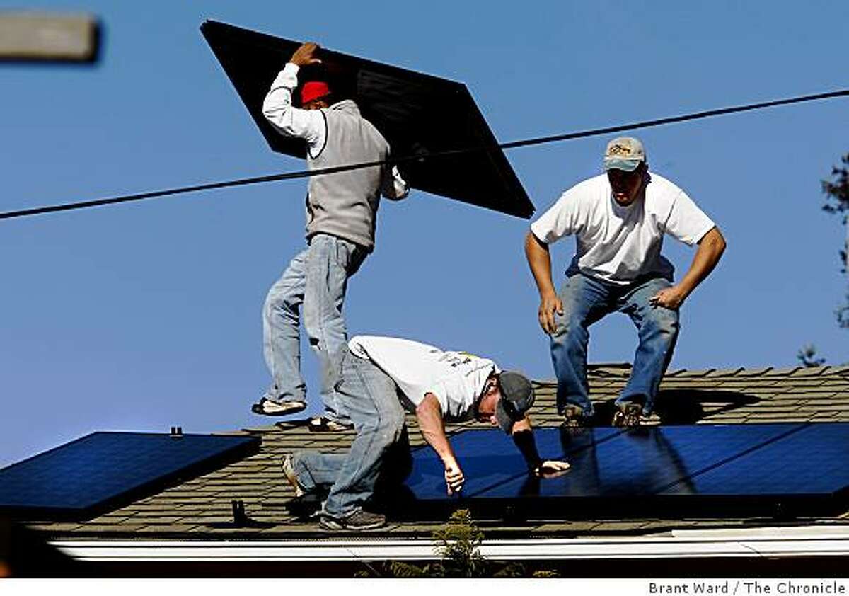 Solar installers Frank Teague (low with screwdriver) and Delmar Oliveira (right) put the panels in place. The solar industry has been a bright spot in a down economy. The Los Gatos based company Akeena Solar is installing 44 solar panels on a home in the Oakland hills Thursday January 15, 2008.