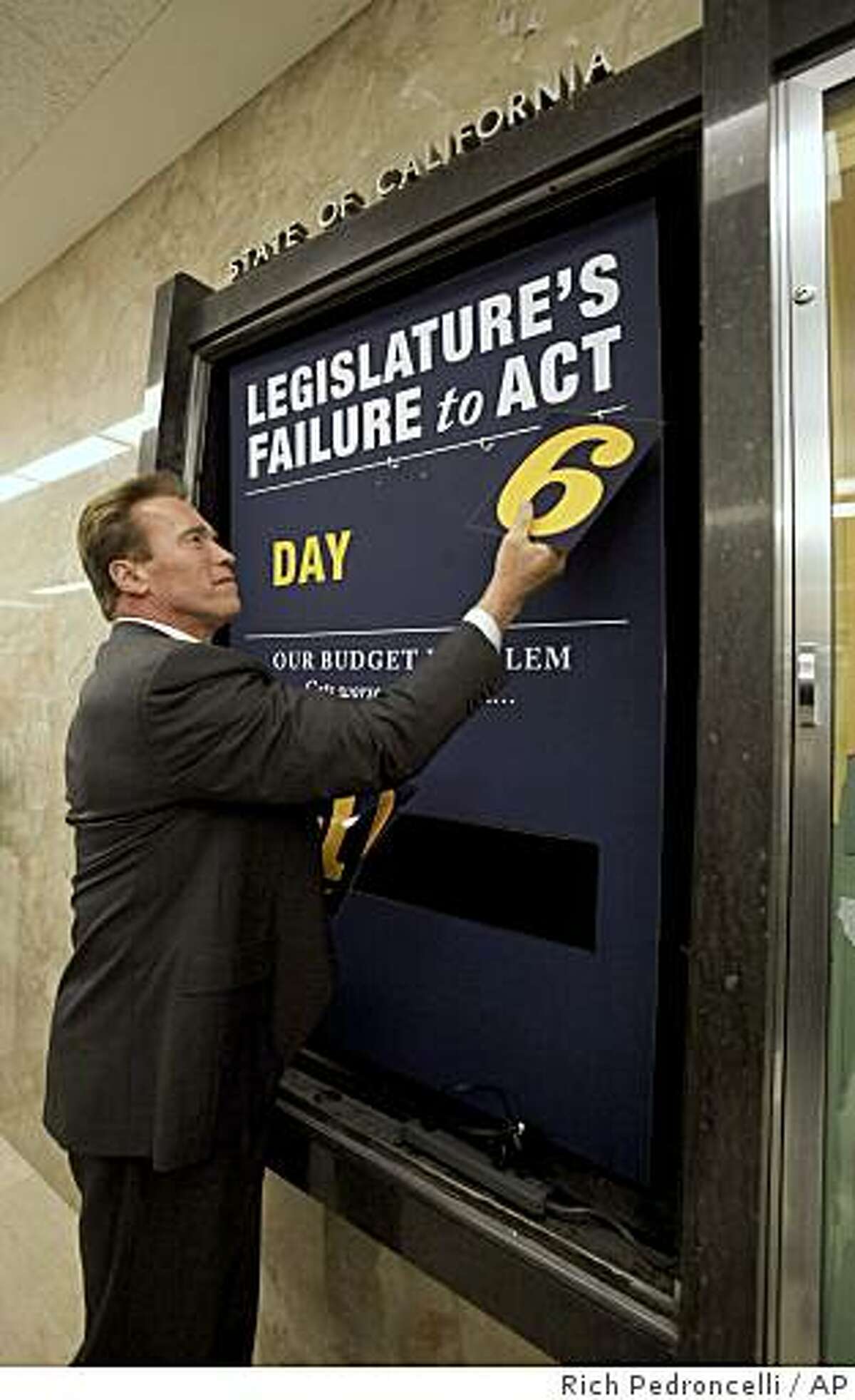 After the Legislatures approval of the state budget, Gov. Arnold Schwarzenegger removes the numbers from the "deficit clock," outside his Capitol office in Sacramento, Calif., Thursday, Feb. 19, 2009. Schwarzenegger had the clock installed 106 days ago to count the number of days that the Legislature failed to act since he declared a special session to deal with the states fiscal problems. (AP Photo/Rich Pedroncelli)