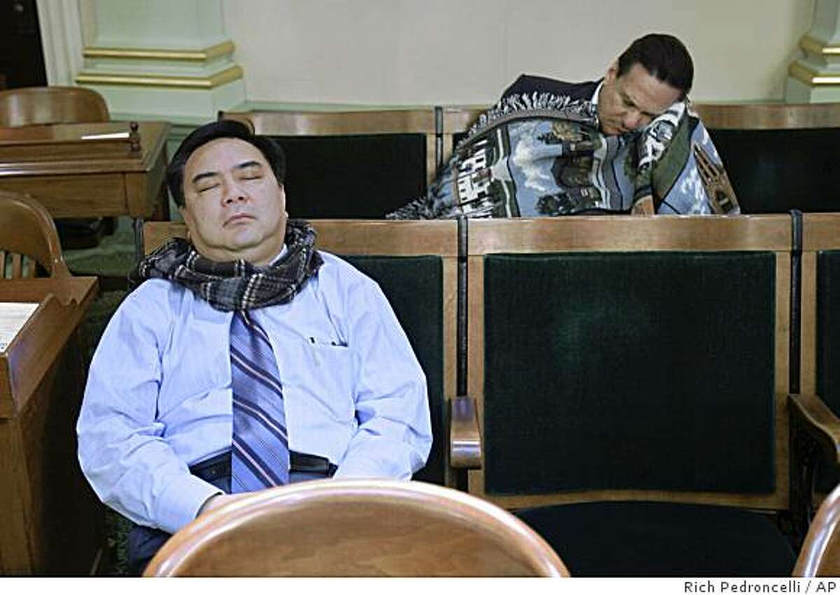 Assembly members Van Tran, R-Costa Mesa, left, and Joe Coto, D-San Jose, right, sleep in the back of the Assembly Chambers in the early morning hours at the Capitol in Sacramento, Calif., Sunday, Feb. 15, 2009. In an effort to get a state budget plan approved, Assembly Speaker Karen Bass, a Democrat, locked down her chamber about 3:30 a.m., forcing members to remain. (AP Photo/Rich Pedroncelli)